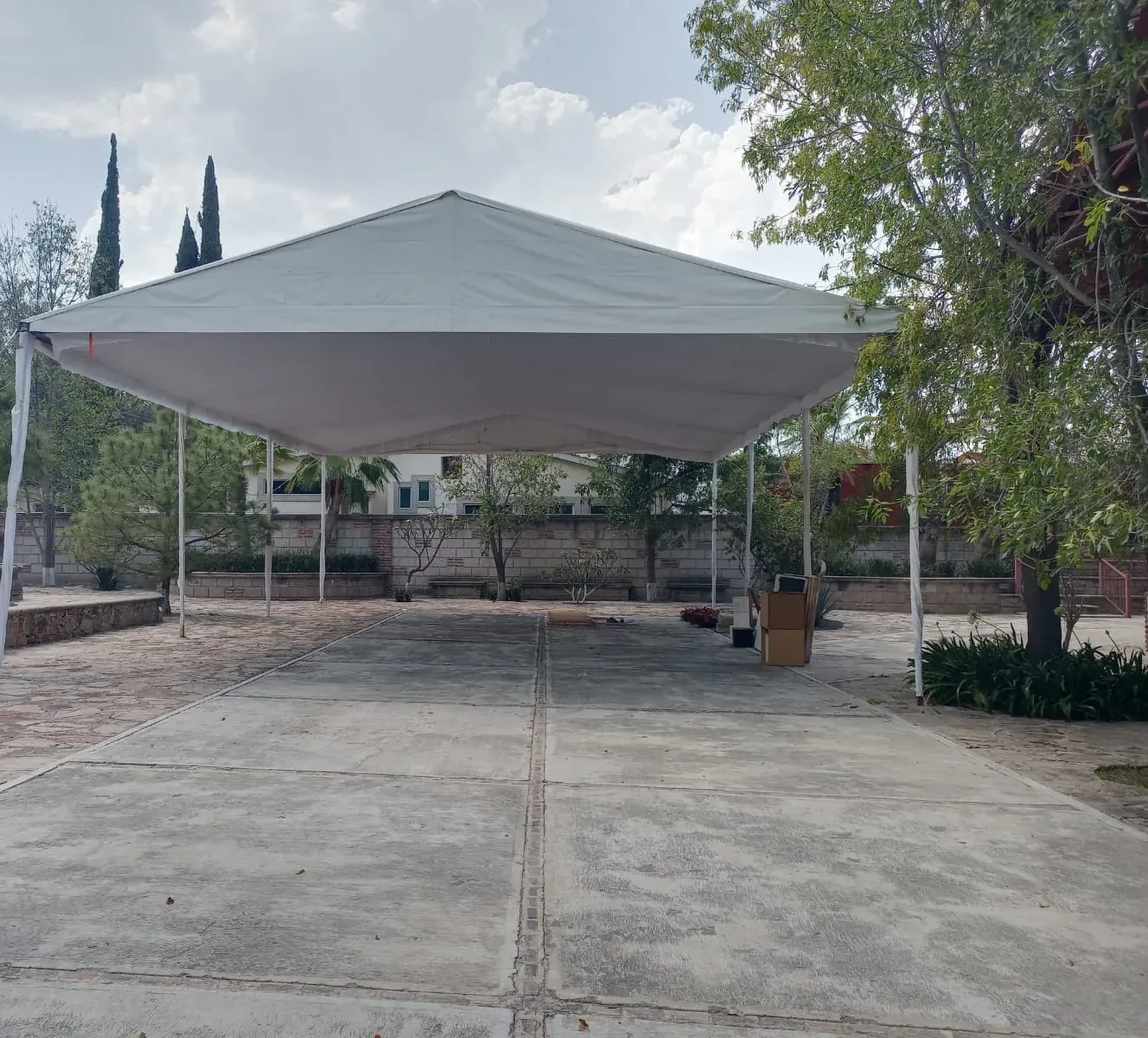Carpa montada sobre una explanada de concreto entre jardines