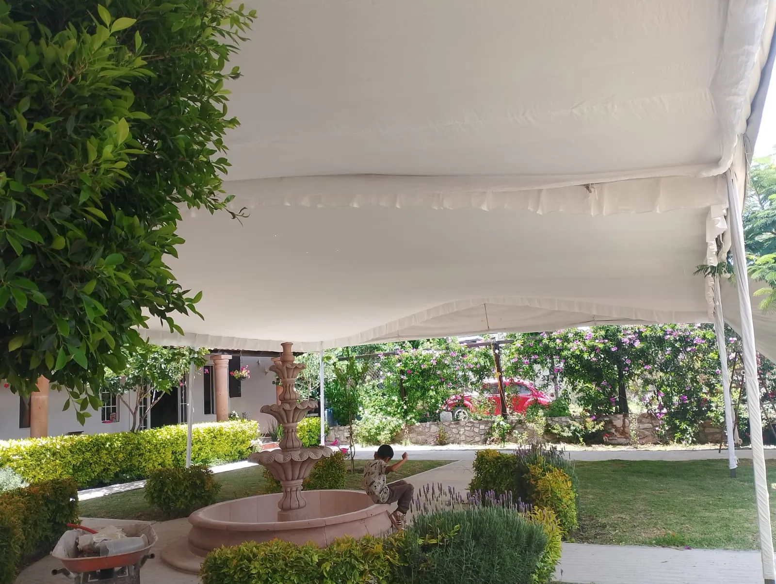 Carpa montada sobre el jardín de una casa, con una fuente de cantera debajo